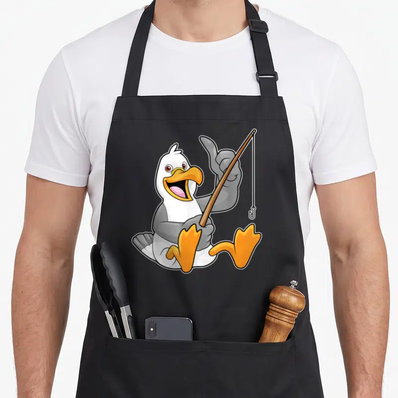 Tablier de cuisine noir avec une mouette blanche et grise tenant une canne à pêche en bois et un crochet métallique.