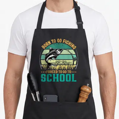 Tablier de cuisine noir avec illustration d'un poisson sautant et texte humoristique sur fond rétro.