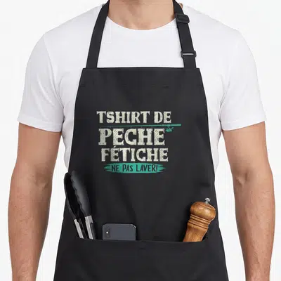 Tablier de cuisine noir avec inscription blanche « Tshirt de Pêche Fétiche » et « Ne Pas Laver » en turquoise.
