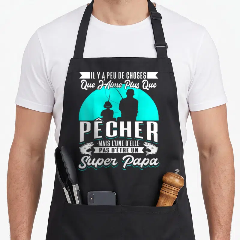 Tablier de cuisine noir avec silhouette de père et enfant en train de pêcher sur fond turquoise et texte blanc humoristique.