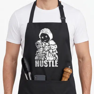 Tablier de cuisine noir avec illustration blanche d'un personnage en veste à capuche et le mot « Hustle » en bas.