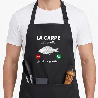 Tablier de cuisine noir avec inscription La carpe m'appelle et illustration de carpe blanche entre deux icônes téléphoniques.