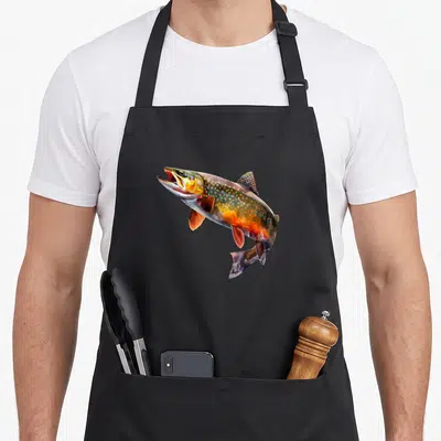 Tablier de cuisine noir avec une illustration colorée d'une truite de ruisseau mouchetée en pleine action.