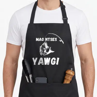 Tablier de cuisine noir avec illustration blanche d'un poisson sautant sous une canne à pêche et le texte Mag ntses yawg.