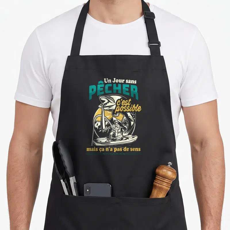 Tablier de cuisine noir avec illustration d'un pêcheur en bateau et un poisson géant sautant hors de l'eau.