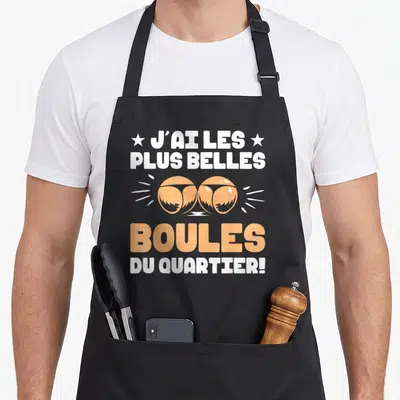 Tablier de cuisine noir avec inscription blanche et orange J'ai les plus belles boules du quartier illustrée par deux boules de pétanque.