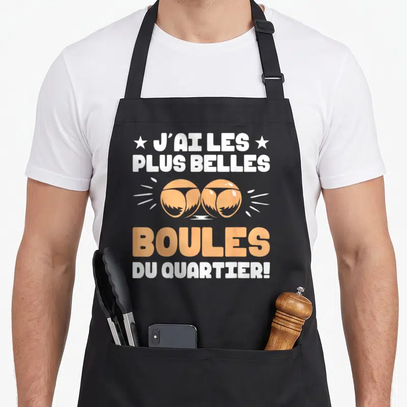 Tablier de cuisine noir avec inscription blanche et orange J'ai les plus belles boules du quartier illustrée par deux boules de pétanque.