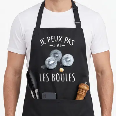 Tablier de cuisine noir avec trois boules de boccia gris et le texte Je peux pas j'ai les boules en blanc.