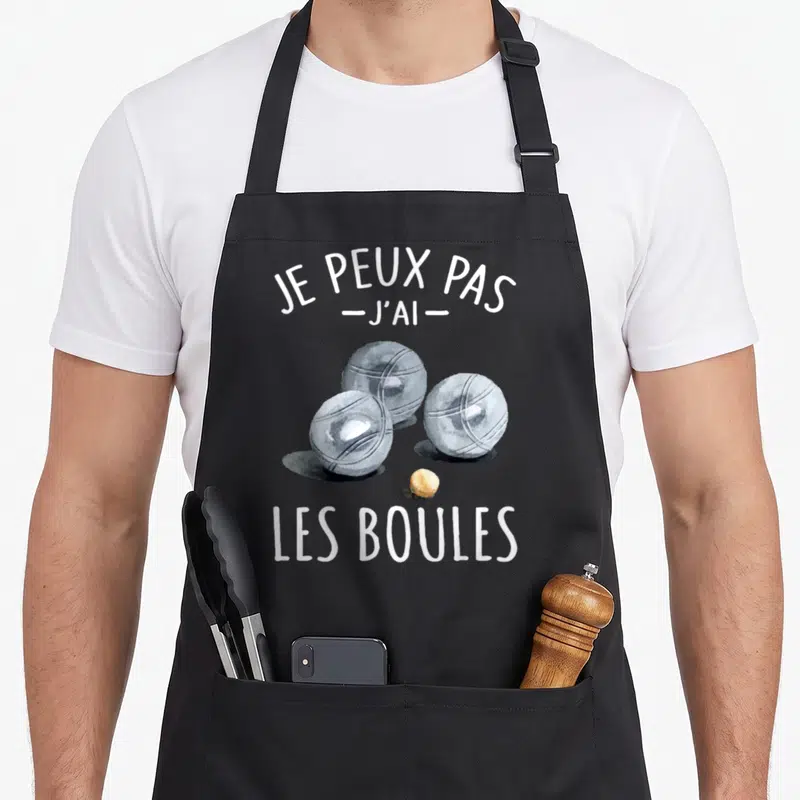 Tablier de cuisine noir avec trois boules de boccia gris et le texte Je peux pas j'ai les boules en blanc.