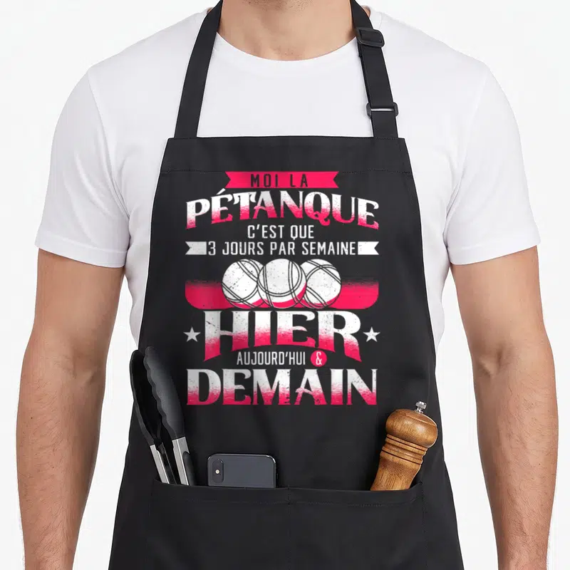 Tablier de cuisine noir avec inscription rose et blanche sur la pétanque et trois boules dessinées au centre.
