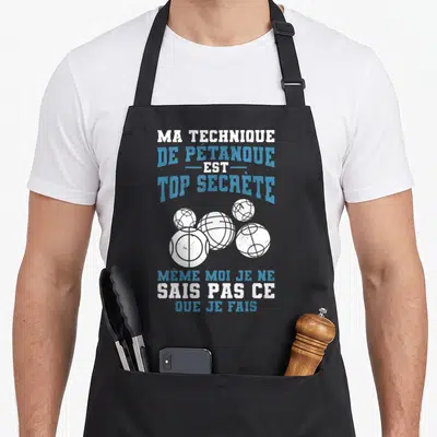 Tablier de cuisine noir avec texte Ma Technique De Pétanque Est Top Secrète et illustration de cinq boules blanches.