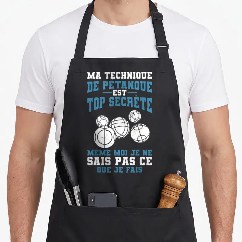 Tablier de cuisine noir avec texte Ma Technique De Pétanque Est Top Secrète et illustration de cinq boules blanches.