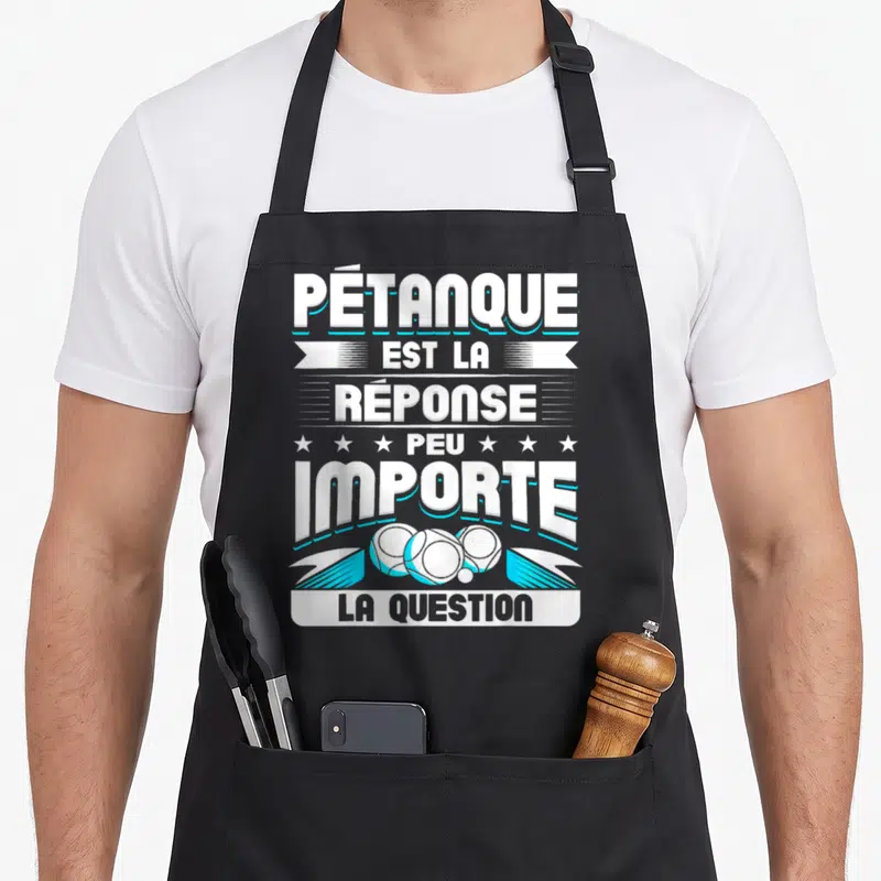 Tablier de cuisine noir avec l'inscription Pétanque est la réponse peu importe la question et trois boules blanches stylisées.