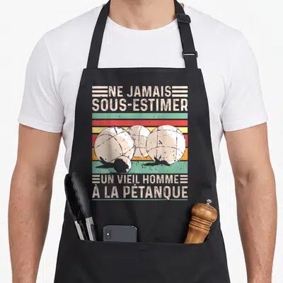 Tablier de cuisine noir avec illustration de boules de pétanque et texte humoristique retro sur bandes colorées.
