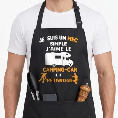 Tablier de cuisine noir avec texte blanc et orange illustrant un camping-car et des silhouettes de joueurs de pétanque.