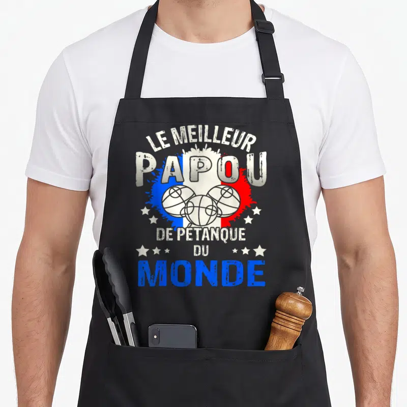 Tablier de cuisine noir avec le meilleur papou de pétanque du monde imprimé en blanc et bleu sur fond de splash tricolore.