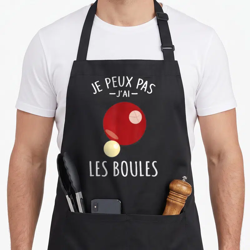 Tablier de cuisine noir avec une boule rouge, une petite boule jaune et le texte Je peux pas j'ai les boules imprimé en blanc.