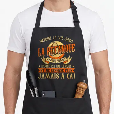 Tablier de cuisine noir avec une boule de pétanque orange et un texte humoristique en jaune sur le devant.