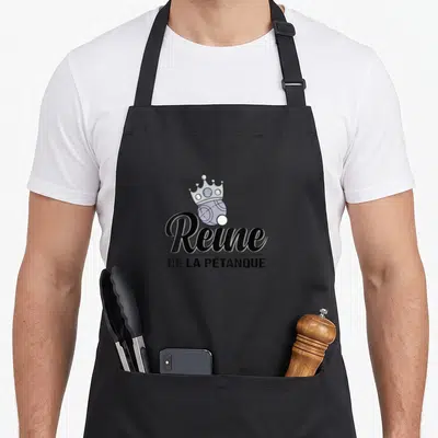 Tablier de cuisine noir avec une boule surmontée d'une couronne et le texte Reine de la Pétanque en typographie élégante.