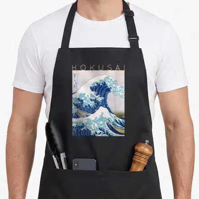 Tablier de cuisine noir avec une reproduction de La Grande Vague de Kanagawa par Hokusai et le nom en haut.