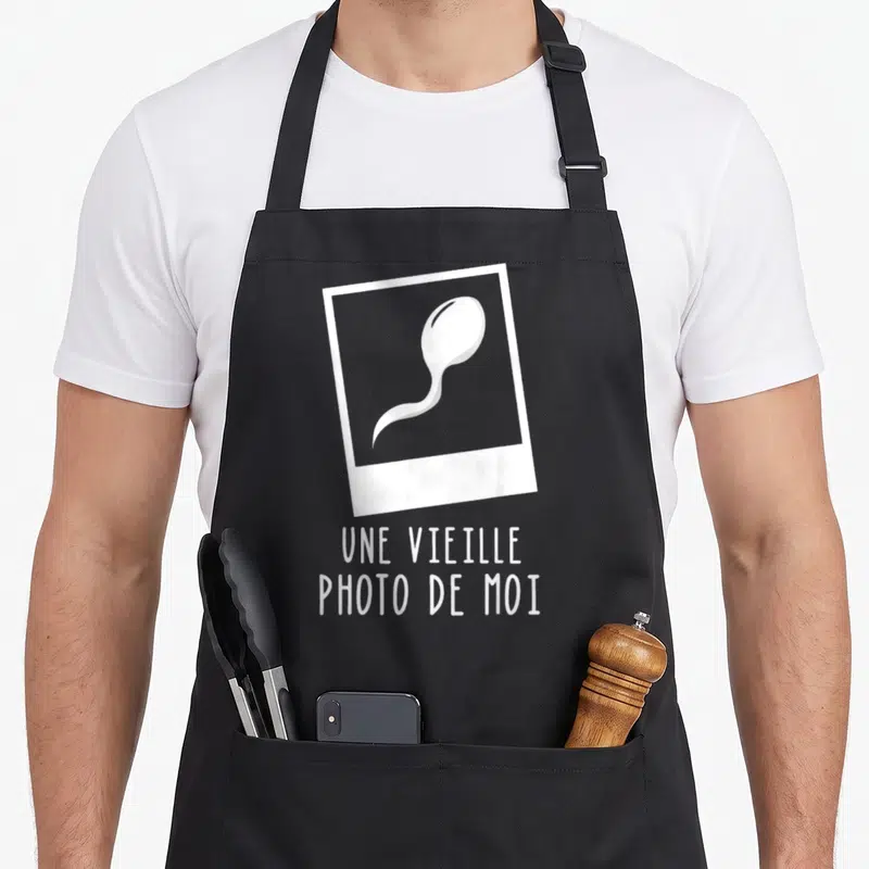 Tablier de cuisine noir avec une vieille photo de moi illustrée par un spermatozoïde en polaroid blanc.