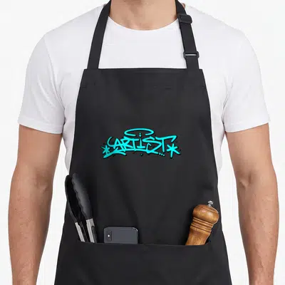 Tablier de cuisine noir avec le mot ARTISTE écrit en lettres de graffiti turquoise et contours noirs.
