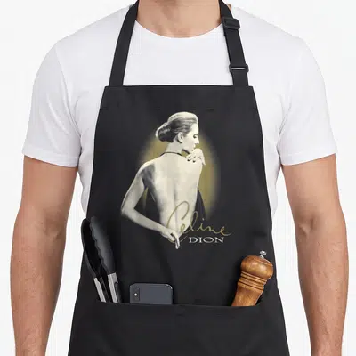 Tablier de cuisine noir avec illustration monochrome dos nu et signature Celine Dion dorée en bas à droite.