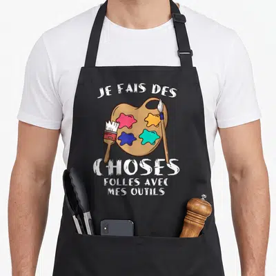 Tablier de cuisine noir avec palette de peintre colorée, deux pinceaux et texte blanc Je fais des choses folles avec mes outils.