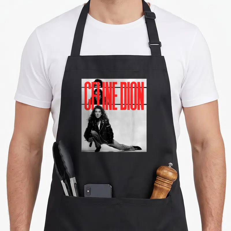 Tablier de cuisine noir avec portrait noir et blanc de Celine Dion et texte rouge vertical.