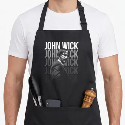 Tablier de cuisine noir avec le texte John Wick en blanc superposé à un portrait en noir et blanc.