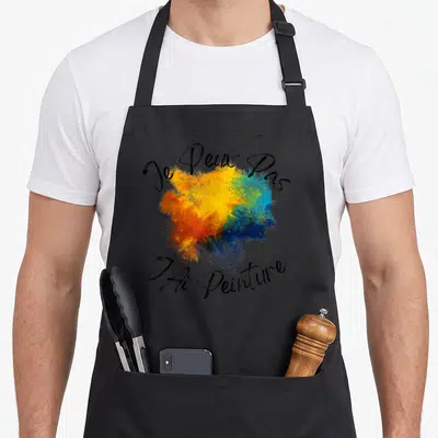 Tablier de cuisine noir avec éclaboussure de couleurs et texte Je Peux Pas JAi Peinture en calligraphie noire.