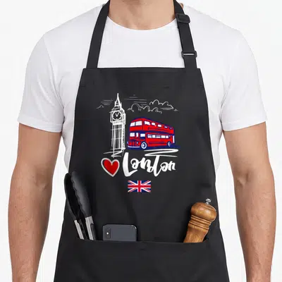 Tablier de cuisine noir avec illustration de bus rouge, Big Ben, cœur rouge et drapeau britannique sous le texte I Love London.