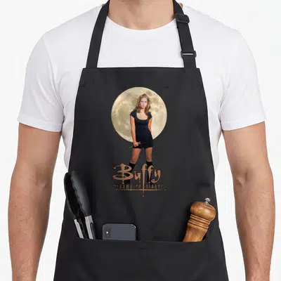 Tablier de cuisine noir avec une photo de Buffy devant une lune et le titre du show imprimé en bas.