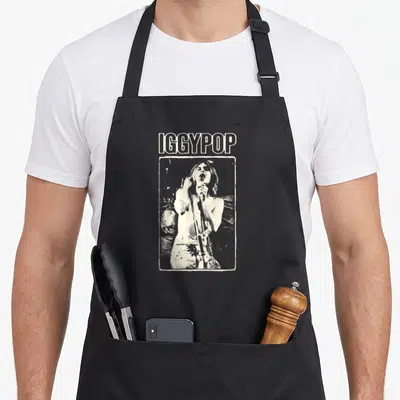 Tablier de cuisine noir avec illustration monochrome d'Iggy Pop tenant un micro et le texte IGGYPOP au-dessus.
