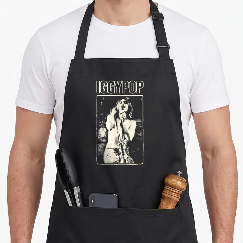 Tablier de cuisine noir avec illustration monochrome d'Iggy Pop tenant un micro et le texte IGGYPOP au-dessus.