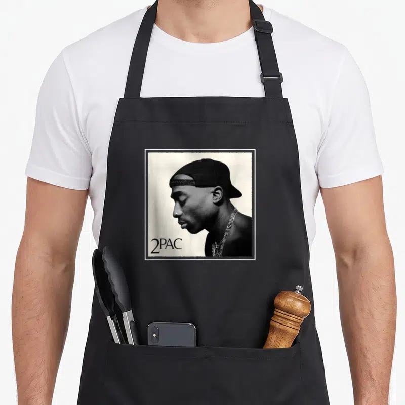 Tablier de cuisine noir avec portrait de profil de 2PAC coiffé d'une casquette et une chaîne en argent.