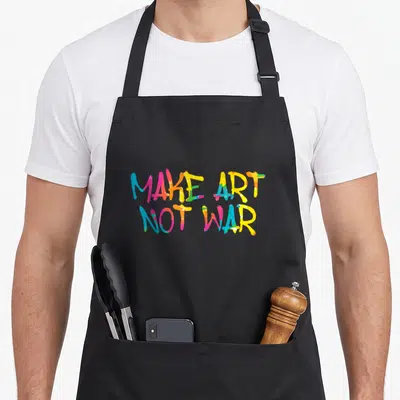 Tablier de cuisine noir avec l'inscription Make Art Not War en lettres graffiti multicolores vives.