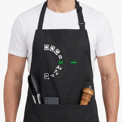 Tablier de cuisine noir avec un dial de mode caméra blanc et vert affichant M, Av, Tv, P et B.