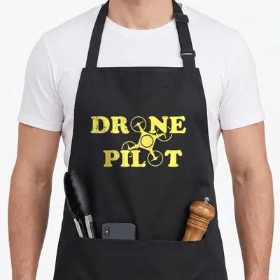 Tablier de cuisine noir avec inscription jaune Drone Pilot et silhouette de drone stylisée au centre du design.