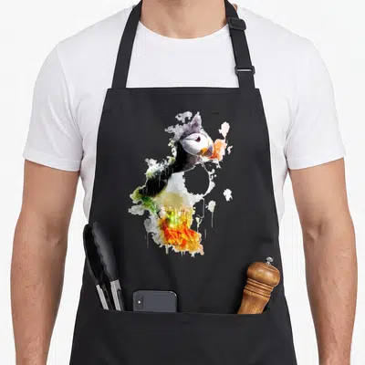 Tablier de cuisine noir avec un macareux atlantique dessiné à l'aquarelle aux couleurs vives et au style minimaliste.