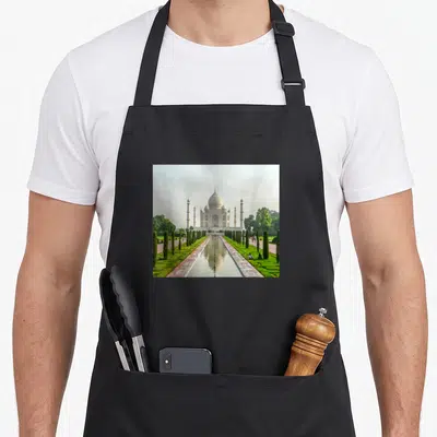 Tablier de cuisine noir avec une impression photographique du Taj Mahal et ses minarets reflétés dans le canal central.