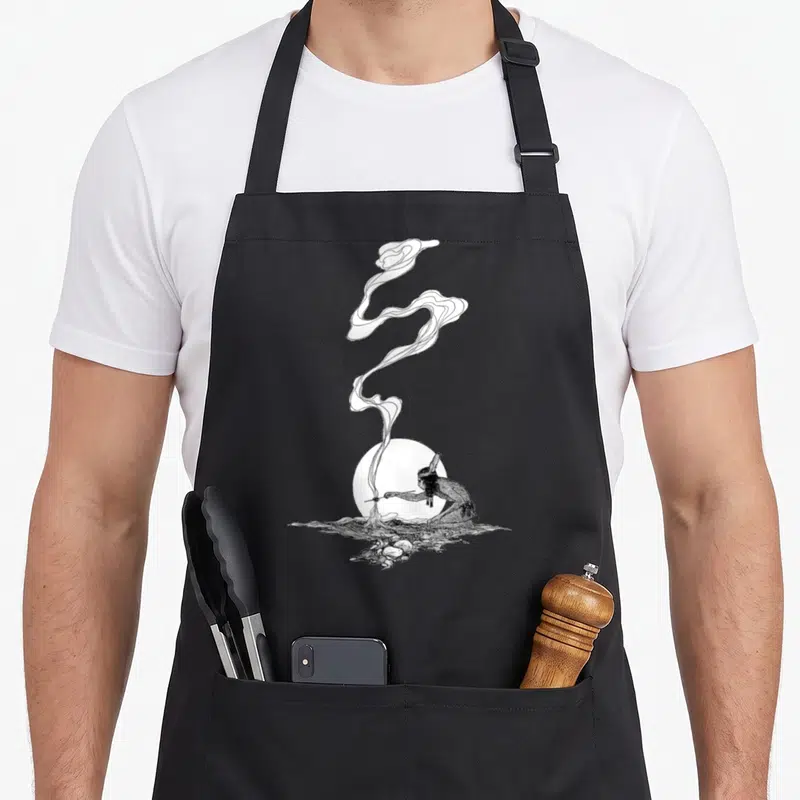 Tablier de cuisine noir avec illustration dessin indien NC Wyeth représentant une fumée ondulante et un disque blanc.