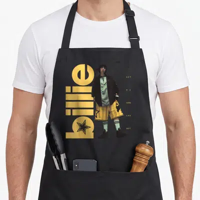 Tablier de cuisine noir avec une illustration de Billie Eilish debout, le texte Hit Me Hard and Soft et des étoiles jaunes.