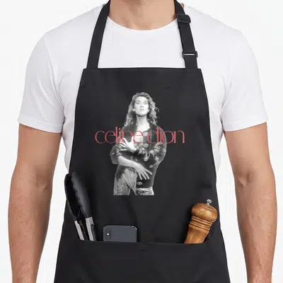 Tablier de cuisine noir avec portrait noir et blanc de Celine Dion et texte rouge celine dion superposé.