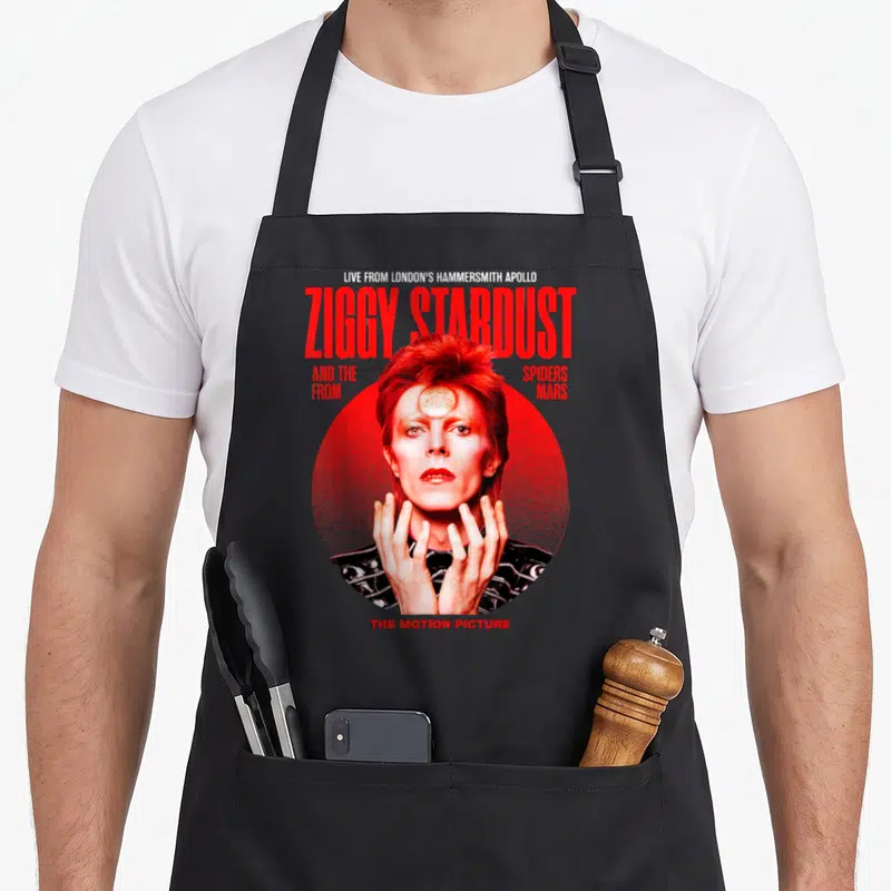 Tablier de cuisine noir avec reproduction du poster Ziggy Stardust et texte rouge en typographie verticale.