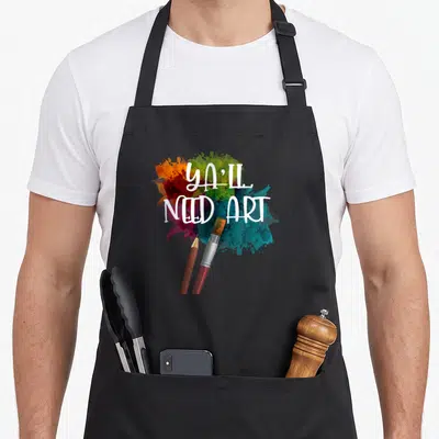 Tablier de cuisine noir avec pinceau, crayon et éclaboussures de peinture multicolore sur le devant.
