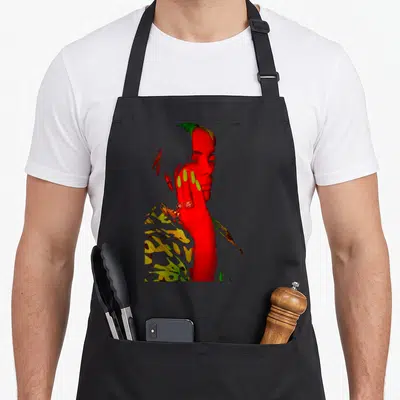 Tablier de cuisine noir avec portrait stylisé rouge et vert fluo d'une femme aux longs ongles et une main sur le visage.