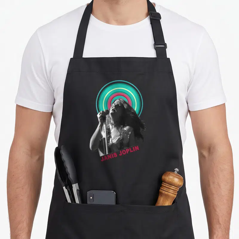 Tablier de cuisine noir avec portrait de Janis Joplin et halo circulaire multicolore.