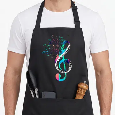Tablier de cuisine noir avec une clé de sol stylisée en touches de piano multicolores et notes dispersées.