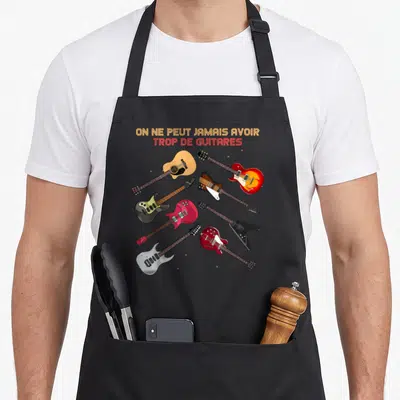 Tablier de cuisine noir avec sept guitares colorées et le texte On ne peut jamais avoir trop de guitares imprimé en haut.